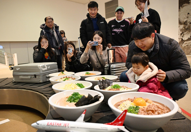 26일 오후 일본 도쿠시마공항에서 열린 '이스타항공 도쿠시마 첫 취항 기념 행사'에서 탑승객들이 공항 수하물 컨베이어 벨트에 전시된 '도쿠시마 라멘 모형'을 관람하고 있다. 이스타항공이 국내 최초로 단독 취항하는 인천-도쿠시마 노선은 주 3회(화, 목, 토) 운항한다. 도쿠시마=권욱 기자 2024.12.26