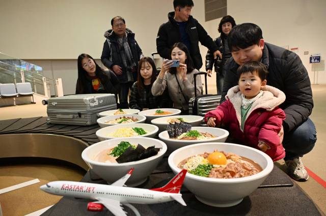 26일 오후 일본 도쿠시마공항에서 열린 '이스타항공 도쿠시마 첫 취항 기념 행사'에서 탑승객들이 공항 수하물 컨베이어 벨트에 전시된 '도쿠시마 라멘 모형'을 관람하고 있다. 이스타항공이 국내 최초로 단독 취항하는 인천-도쿠시마 노선은 주 3회(화, 목, 토) 운항한다. 도쿠시마=권욱 기자 2024.12.26