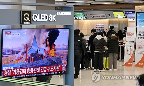 무안국제공항 여객기 참사가 발생한 29일 서울 강서구 김포국제공항 국내선 청사에서 관련 뉴스가 나오는 가운데 제주항공 승객들이 탑승 수속을 하고 있다. 연합뉴스