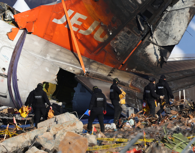 제주항공 여객기 참사 7일째인 4일 오후 무안국제공항 사고 현장에서 마무리 수색 작업을 하던 경찰특공대원들이 구명 조끼를 들고 현장을 나서고 있다. 연합뉴스