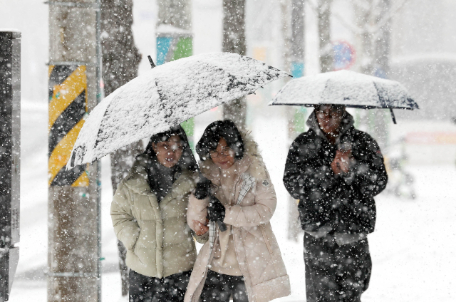 대설 특보가 발표된 7일 오전 눈이 내리는 광주 북구청 일대에서 시민들이 우산을 쓰고 걷고 있다. 연합뉴스