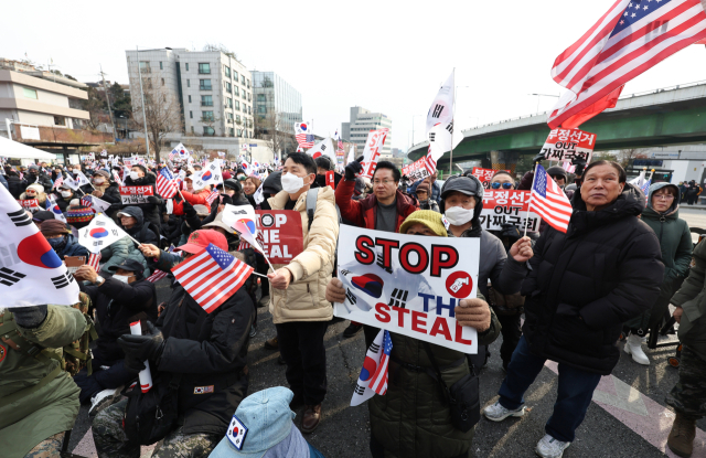 법원이 윤석열 대통령에 대한 체포영장을 재발부해 공조수사본부 차원의 영장 2차 집행 시도가 초읽기에 들어간 8일 오후 서울 용산구 한남동 대통령 관저 인근에서 보수단체가 주최한 탄핵 반대 집회에서 손팻말을 들고 있다. 연합뉴스