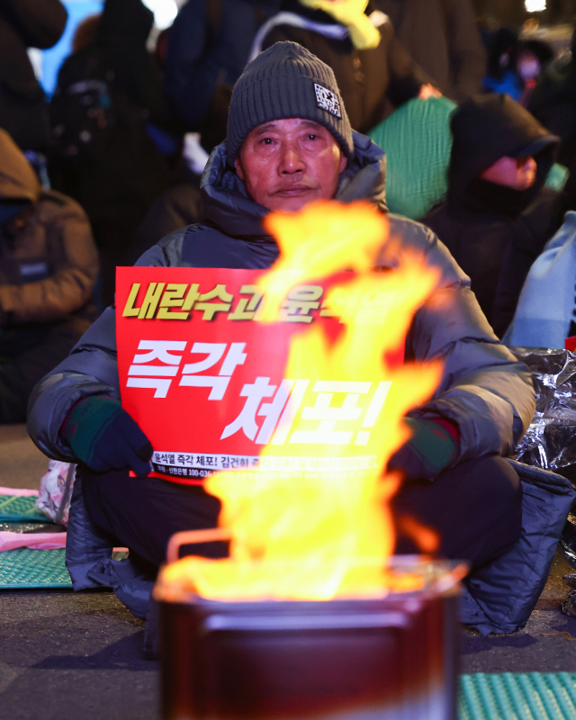 9일 오후 서울 용산구 한남동 대통령 관저 인근에서 열린 윤석열 대통령 탄핵 촉구 집회에서 한 참가자가 팻말을 들고 있다.연합뉴스