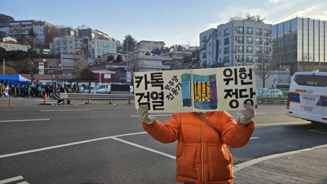 12일 서울 용산구 한남동 대통령 관저 맞은편에서 보수 단체 지지자가 직접 제작한 피켓을 들고 있다. 이승령 기자