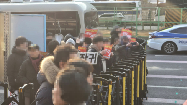 12일 서울 용산구 한남동 대통령 관저 인근에서 진보 단체 지지자들이 인근에서 열린 보수단체 지지자들의 집회 방향으로 피켓을 흔들며 구호를 외치고 있다. 이승령 기자