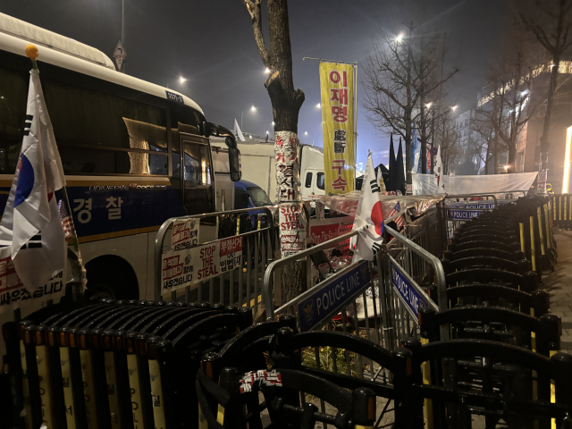 14일 오전 6시 30분께 서울 용산구 한남동 대통령 관저 인근 모습. 일부 집회 참가자들이 펜스와 경찰 저지선 사이에 비닐을 덮고 들어가 있다. 장형임기자