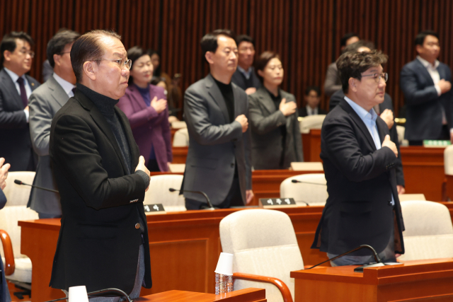 권영세 국민의힘 비상대책위원장과 권성동 원내대표를 비롯한 의원들이 15일 서울 여의도 국회에서 열린 비상 의원총회에서 국기에 경례하고 있다. 연합뉴스