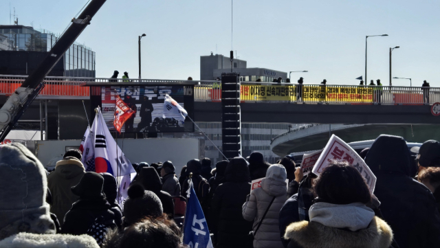 15일 오전 서울 용산구 한남동 대통령 관저 인근에서 집회를 하던 보수단체 집회 참석자들이 윤석열 대통령 체포 소식을 듣고 있다. 이승령 기자