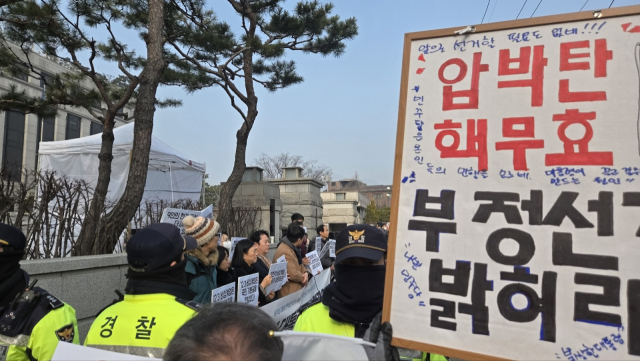 21일 서울 종로구 헌법재판소 앞에서 경제정의실천시민연합(경실련)이 윤석열 대통령 탄핵심판 관련 의견서 제출 및 비상게엄 기본권 침해 헌법소원 청구 기자회견을 개최한 가운데, 윤 대통령의 지지자들이 피켓을 들고 반발하고 있다. 이승령 기자