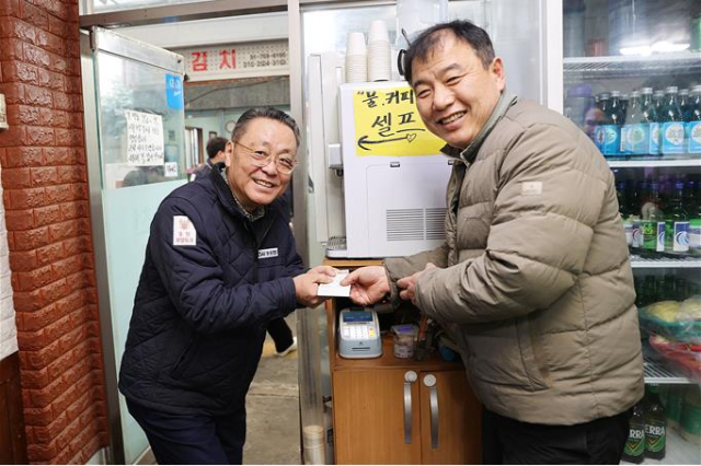 ‘부산형 착한결제 캠페인’에 동참한 장호익(왼쪽) 동원개발 부회장이 수영구 수영팔도시장 인근 식당에서 선결제를 하며 기념촬영을 하고 있다. 사진제공=부산시