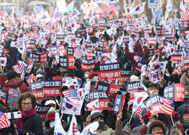 윤석열 대통령의 탄핵심판 3차 변론이 열리는 21일 서울 종로구 헌법재판소 인근에서 윤 대통령 지지자들이 집회를 열고 탄핵 무효를 주장하는 구호를 외치고 있다. 연합뉴스