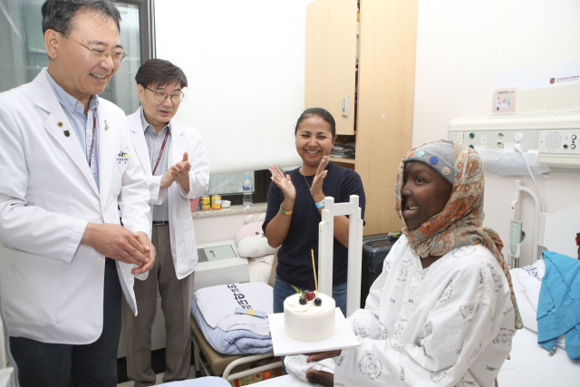 ‘글로벌 호의 생명사랑 프로젝트’의 일환으로 섬나라 마다가스카르에서 온 횡문근육종 환자 라소아리만나나 에프라지(오른쪽) 씨가 고대안암병원에서 성공적으로 수술을 마치고 의료진들과 기념사진을 찍었다. 에프라지는 고대안암병원 소아청소년과 박준은 교수, 이비인후과 백승국 교수, 성형외과 정재호 교수의 다학제 협진으로 3주간의 항암치료와 종양 제거 수술을 성공적으로 마쳤고 이후 2개월의 방사선 치료를 거쳐 이전 얼굴을 최대한 회복할 수 있었다. 종양이 가리고 있던 오른쪽 눈의 시야도 확보됐다. 사진 제공=고려대의료원