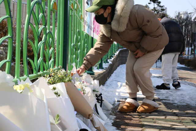 11일 오전 초등생 1학년 여아가 살해당한 대전 서구 한 초등학교에 한 시민이 추모한 뒤 과자를 놓고 가고 있다. 연합뉴스