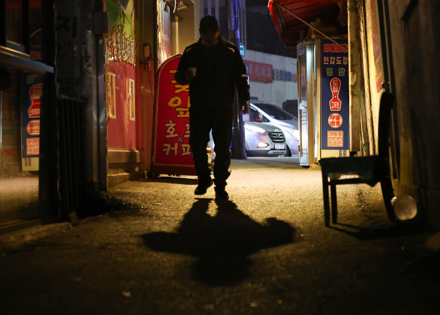 18일 새벽 인력사무소가 밀집한 서울 남구로역 인근 골목에 일감을 구하려는 일용직 구직자의 그림자가 길게 드리워져 있다. 연합뉴스.