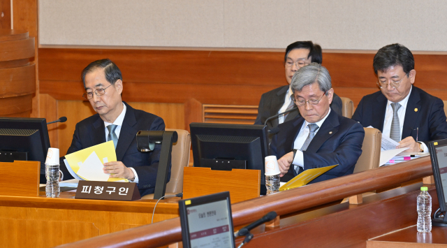 한덕수(왼쪽) 국무총리가 19일 서울 종로구 헌법재판소 대심판정에서 열린 한 총리 탄핵 심판 1차 변론기일에서 출석해 자료를 살펴보고 있다. 뉴스1