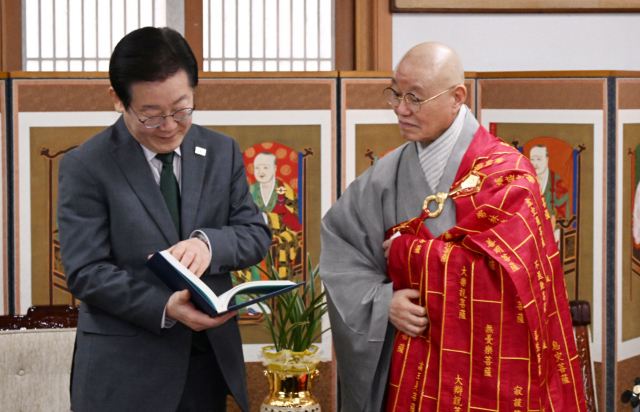 이재명(왼쪽) 더불어민주당 대표가 24일 서울 종로구 한국불교태고종 총무원에서 총무원장인 상진 스님에게 책을 선물하고 있다. 연합뉴스