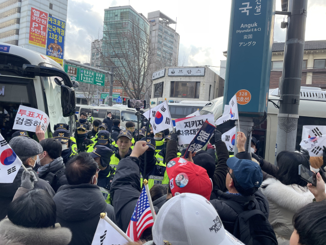 탄핵 반대 시위대가 윤석열 대통령 호송차량이 지나간다는 소식에 태극기를 치켜들며 환호하고 있다. 장문항 견습기자