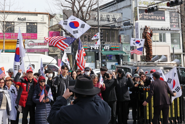 27일 광주 북구 용봉동 전남대학교 후문 앞에서 재학생 일부와 보수 단체 회원들이 태극기를 흔들며 구호를 외치고 있다. 연합뉴스