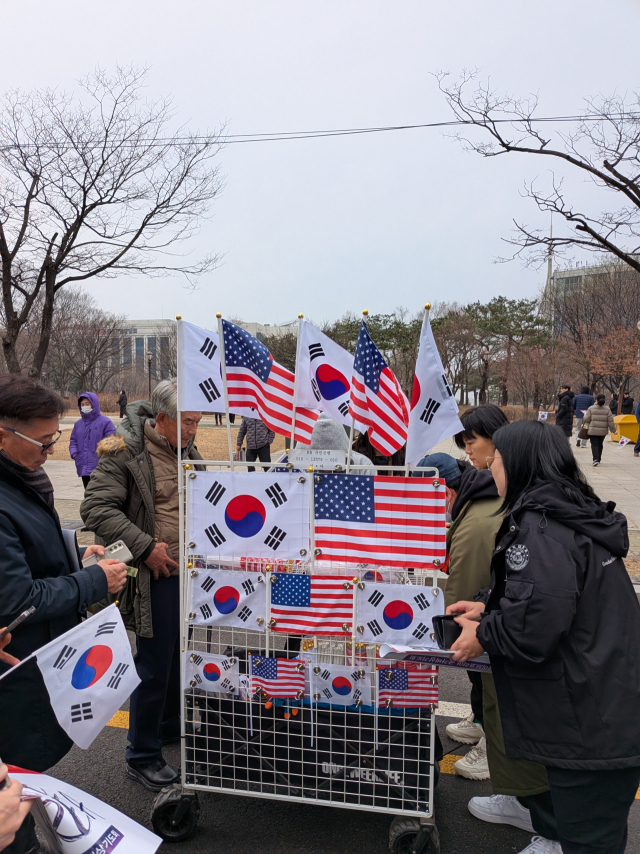 1일 서울 영등포구 마포대교 남단 세이브코리아 ‘국기비상기도회’ 집회 현장에서 깃발을 준비하지 않은 참가자들이 태극기와 성조기를 구매하고 있다. 황동건 기자