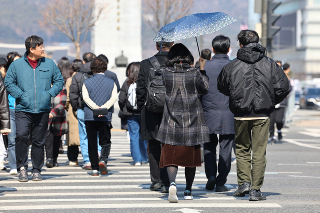 서울 최고기온이 10도까지 오르며 따듯한 날씨를 보인 6일 서울 종로구 광화문 네거리에서 한 시민이 양산을 들고 길을 건너고 있다.연합뉴스