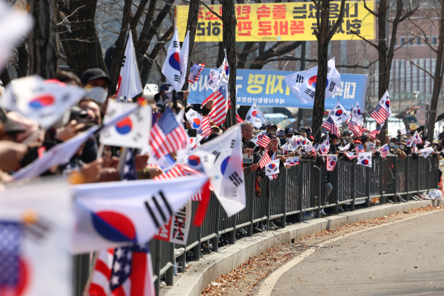 법원의 윤석열 대통령 구속 취소 결정을 두고 검찰의 입장 발표가 늦어지고 있는 가운데 8일 경기도 의왕시 서울구치소 앞에서 윤 대통령 지지자들이 석방을 기대하며 태극기와 성조기를 흔들고 있다. 연합뉴스