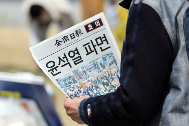 4일 헌법재판소가 윤석열 대통령 파면을 선고한 전라남도 광주 동구 5·18민주광장에서 한 시민이 전남일보 호외를 읽고 있다. 연합뉴스