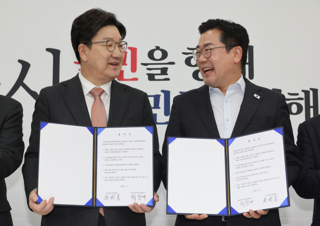 권성동(왼쪽) 국민의힘 원내대표와 박찬대 더불어민주당 당대표 직무대행 겸 원내대표가 추경안 합의문에 서명한 뒤 미소짓고 있다. 연합뉴스