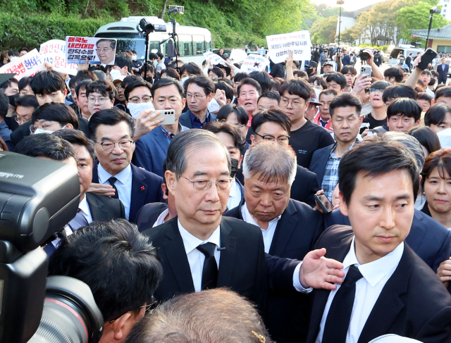 2일 오후 광주 북구 국립 5·18민주묘지를 찾은 한덕수 전 총리가 광주비상행동 등 시민사회단체 관계자들에게 가로막히자 발길을 돌리고 있다. 연합뉴스