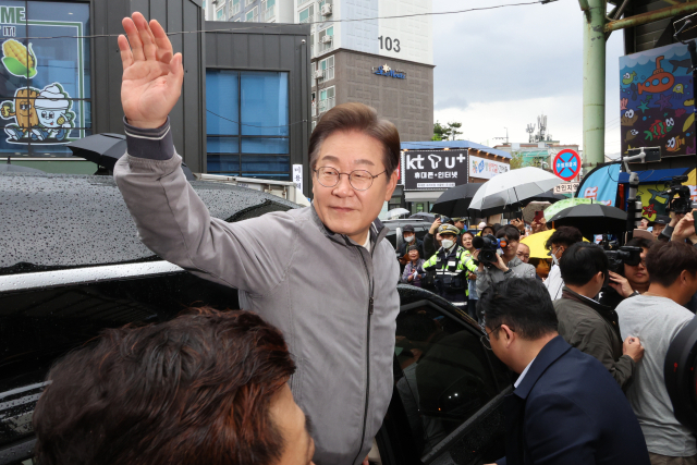 이재명 대선 후보가 '골목골목 경청투어' 사흘째인 3일 '동해안벨트' 첫 방문지인 강원도 속초시 중앙재래시장에서 강원도민들을 만난 뒤 차에 올라 인사하고 있다. 연합뉴스