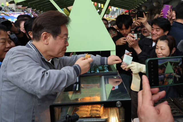 이재명 더불어민주당 대선 후보가 '골목골목 경청투어' 사흘째인 3일 강원도 태백시 장성동 산나물 축제장에서 붕어빵을 사먹으며 지역화폐를 사용하고 있다. 연합뉴스