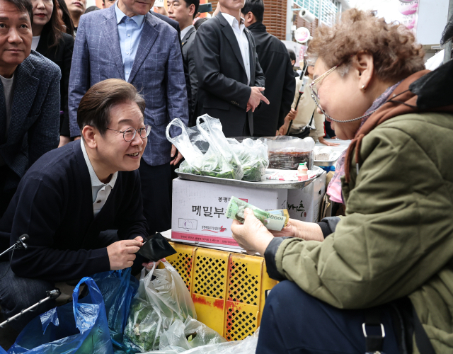 이재명 더불어민주당 대선 후보가 '골목골목 경청투어' : 단양8경편'에 나선 4일 강원도 영월군 영월서부시장에서 나물을 구입하며 상인과 대화하고 있다. 연합뉴스