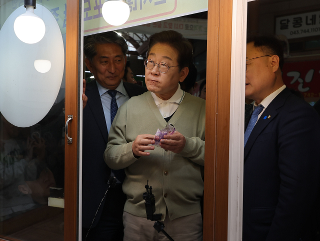 이재명 더불어민주당 대선 후보가 '골목골목 경청투어:국토종주편'에 나선 6일 충북 영동군 영동전통시장의 한 떡집에서 떡을 사먹고 있다. 연합뉴스
