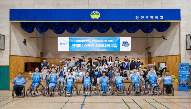 코웨이 블루휠스 휠체어농구단이 남양주 창현초등학교에서 열린 ‘어린이 휠체어농구 체험교실’ 행사 후, 참가 학생들과 함께 기념촬영을 하고 있다. 사진 제공=코웨이