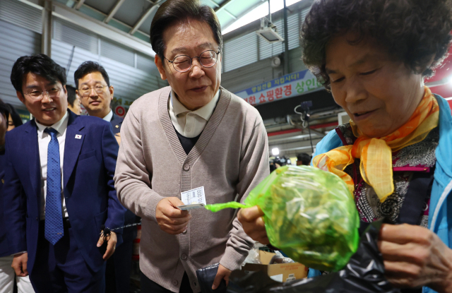 더불어민주당 이재명 대선 후보가 제3차 골목골목 경청투어로 경북지역 방문에 나선 9일 경북 영천시 영천공설시장을 찾아 한 가게에서 영천사랑상품권으로 말린 고추를 구매하고 있다. 연합뉴스