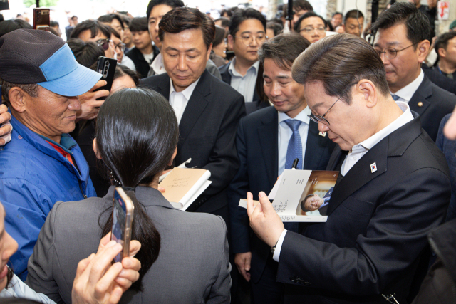 경청투어에 나선 이재명 더불어민주당 대통령 후보가 10일 오전 경남 의령군 의령읍 의령전통시장에서 책에 사인하고 있다. 뉴스1