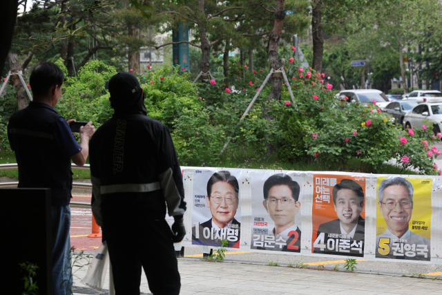 서울 마포구 공덕역 일대에 붙은 제21대 대통령 선거 벽보 뒤로 장미꽃이 활짝 펴 있다. 연합뉴스