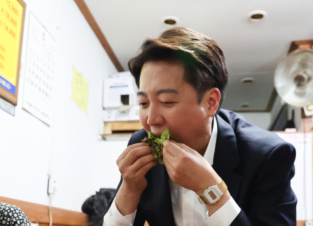 이준석 개혁신당 대선 후보가 16일 충남 천안중앙시장에서 유세 도중 한 시민이 건넨 쌈을 맛보고 있다.