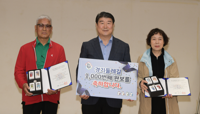 조원용 경기관광공사 사장이 20일 수원 공사에서 열린 창립기념일 행사에서 경기둘레길 1000번째 완보자인 이은영씨 부부에게 완보증과 기념품을 전달하고 있다. 사진 제공 = 경기관광공사