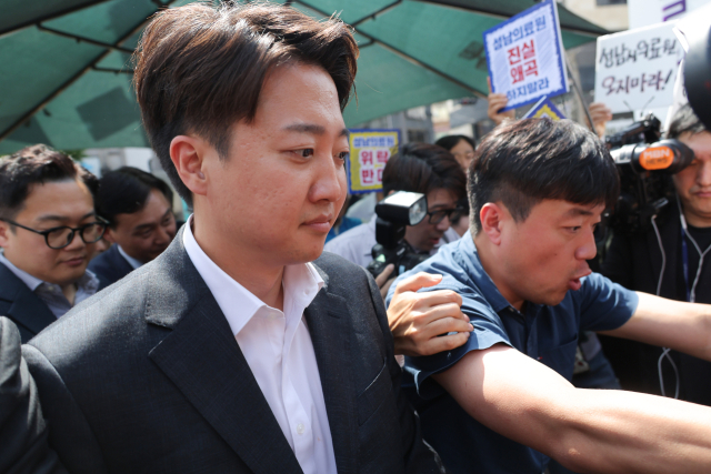 이준석 개혁신당 대선 후보가 21일 경기 성남의료원에 도착, 시민단체 회원들의 항의를 받으며 들어서고 있다. 연합뉴스