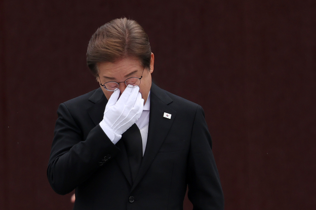 이재명 더불어민주당 대선 후보가 23일 경남 김해시 봉하마을을 방문해 노무현 전 대통령 묘역을 참배한 뒤 눈물을 훔치고 있다. 연합뉴스