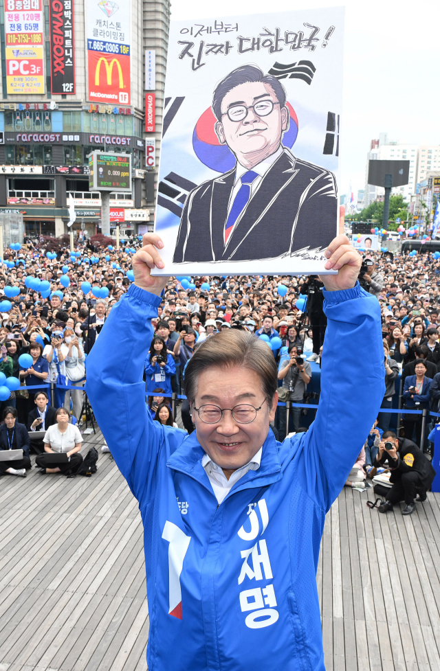이재명 더불어민주당 대선 후보가 24일 경기 부천시 부천역 광장에서 유세 시작 전 선물 받은 케리커쳐를 들어 보이고 있다. 부천=오승현 기자 2025.02.24