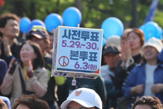 26일 이재명 더불어민주당 대선 후보의 유세가 열린 경기 남양주시 평내호평역 광장에서 한 시민이 사전투표와 본투표 날짜가 적힌 피켓을 들고 투표를 독려하고 있다. 연합뉴스