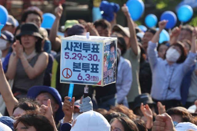26일 더불어민주당 이재명 대선 후보의 유세가 열린 경기 남양주시 평내호평역 광장에서 한 시민이 사전투표와 본투표 날짜가 적힌 피켓을 들고 투표를 독려하고 있다. / 연합뉴스