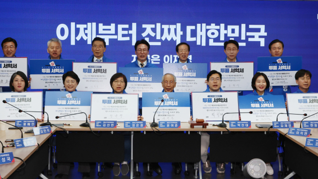 더불어민주당 윤여준·박찬대 상임 총괄선대위원장을 비롯한 공동선대위원장들이 사전투표를 하루 앞둔 28일 서울 여의도 당사에서 열린 중앙선거대책위원회의에서 투표서약서에 서명 후 유권자들에게 투표를 독려하고 있다. 연합뉴스