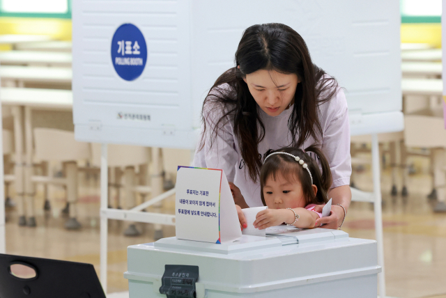 제21대 대통령 선거일인 3일 서울 서초구 서울중학교에 마련된 서초2동제4투표소에서 유권자가 아이와 함께 투표 용지를 투표함에 넣고 있다. 연합뉴스