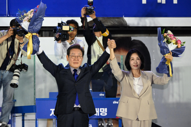 당선이 확실시된 이재명 더불어민주당 대선 후보가 김혜경 여사와 4일 오전 서울 여의도 국회 앞을 찾아 꽃다발을 들어보이고 있다.뉴스1