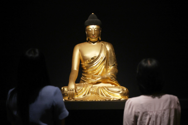 9일 서울 용산구 국립중앙박물관에서 열린 용산 개관 20주년 기념 특별전 ‘새 나라 새 미술: 조선 전기 미술 대전’에서 관계자가 ‘조계사 목조여래좌상’을 감상하고 있다. 연합뉴스