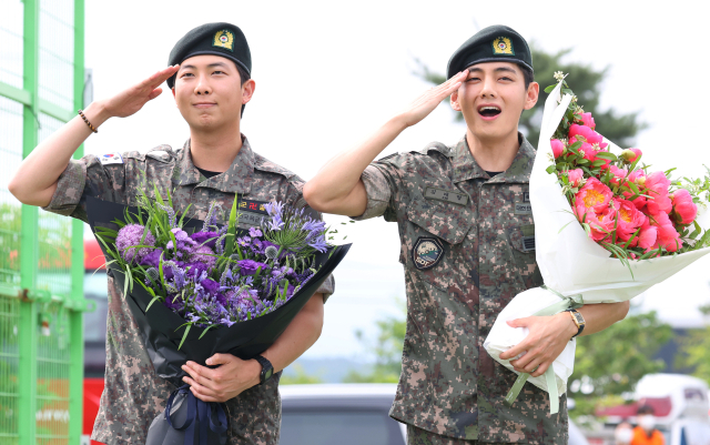 군 복무를 마치고 전역한 방탄소년단(BTS) RM(왼쪽)과 뷔가 10일 강원 춘천시 신북읍체육공원에서 거수경례를 하고 있다. 연합뉴스