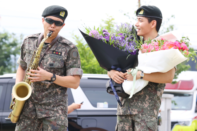 10일 군 복무를 마치고 전역한 방탄소년단(BTS) RM(왼쪽)이 뷔가 지켜보는 가운데 색소폰 연주를 하고 있다. 연합뉴스