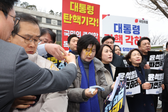 백혜련 의원이 3월 20일 서울 종로구 헌법재판소 앞에서 열린 더불어민주당 원내부대표단의 윤석열 대통령 신속 파면 촉구 기자회견 도중 맞은 계란을 닦아내고 있다. 연합뉴스